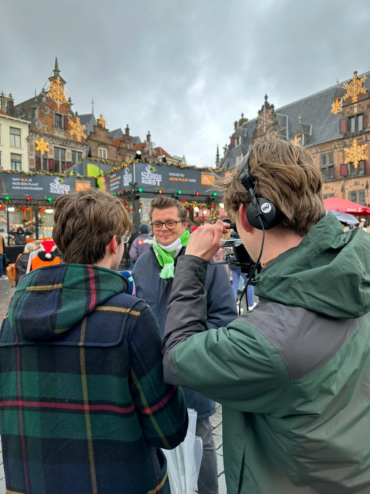 Luca van achteren tijdens een interview op locatie, naast een collega met camera.