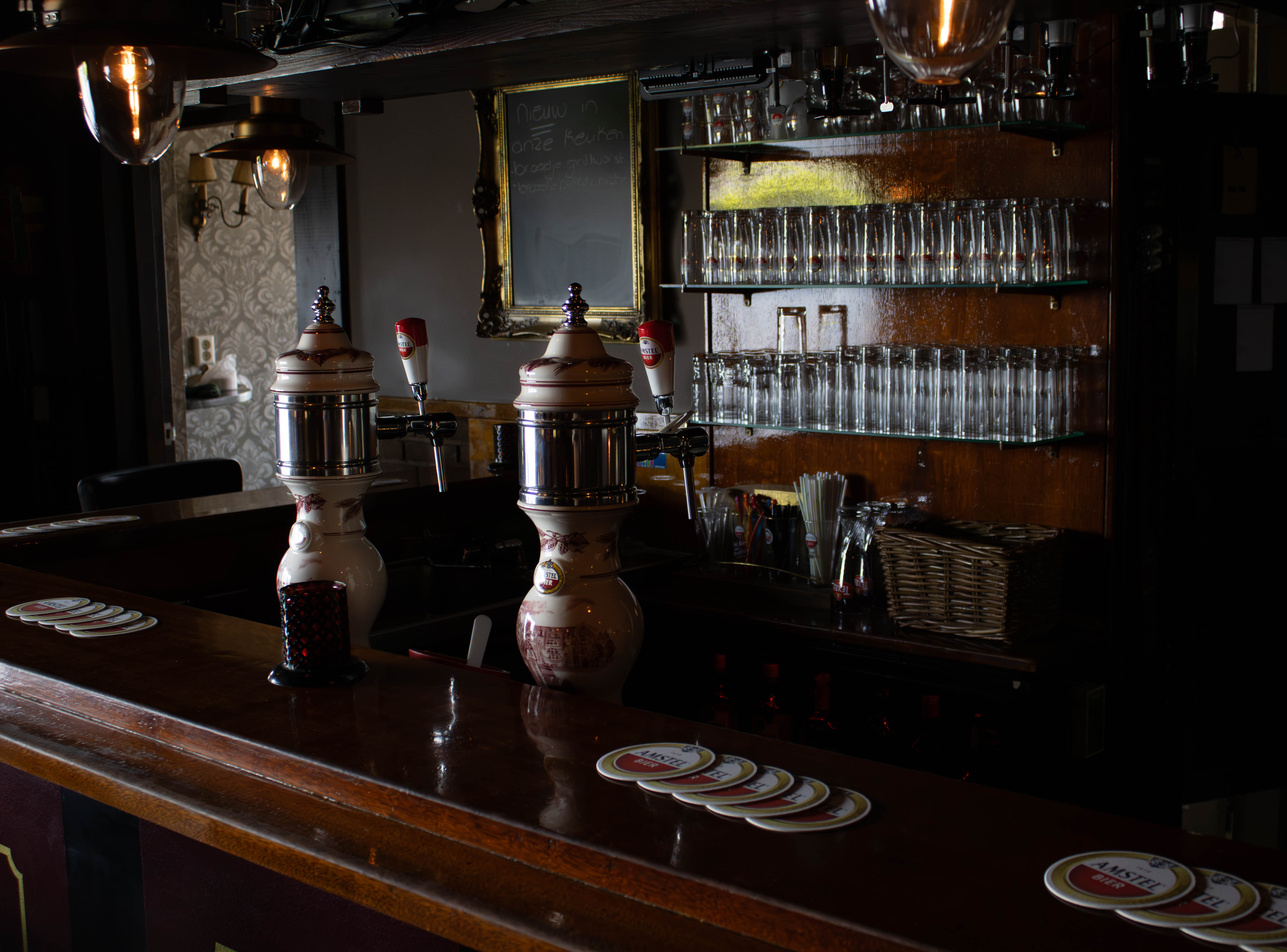 De lege bar van Café de Lamp, met porseleinen biertappen en rijen glazen