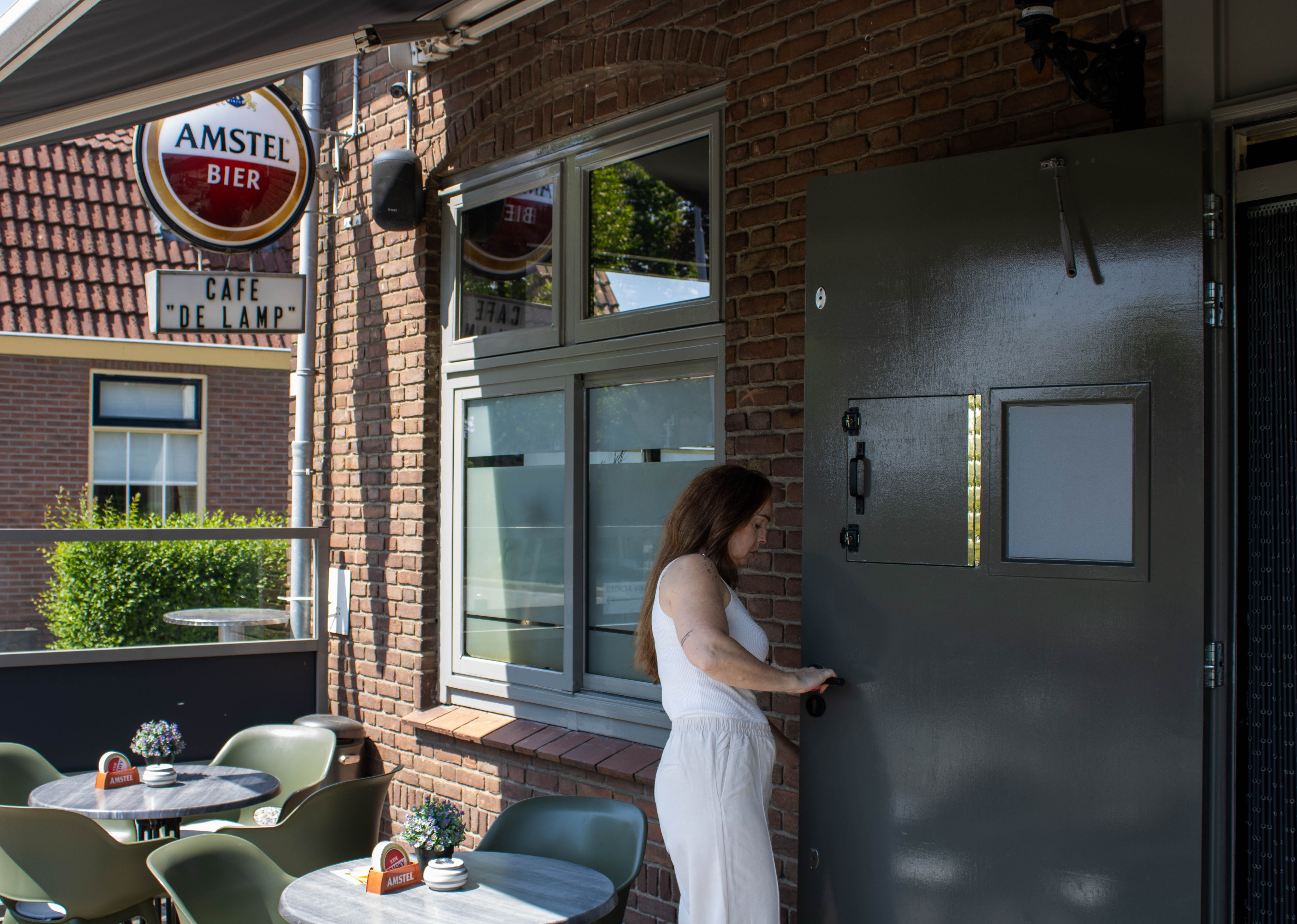De eigenaresse van Café de Lamp opent de deur van het café