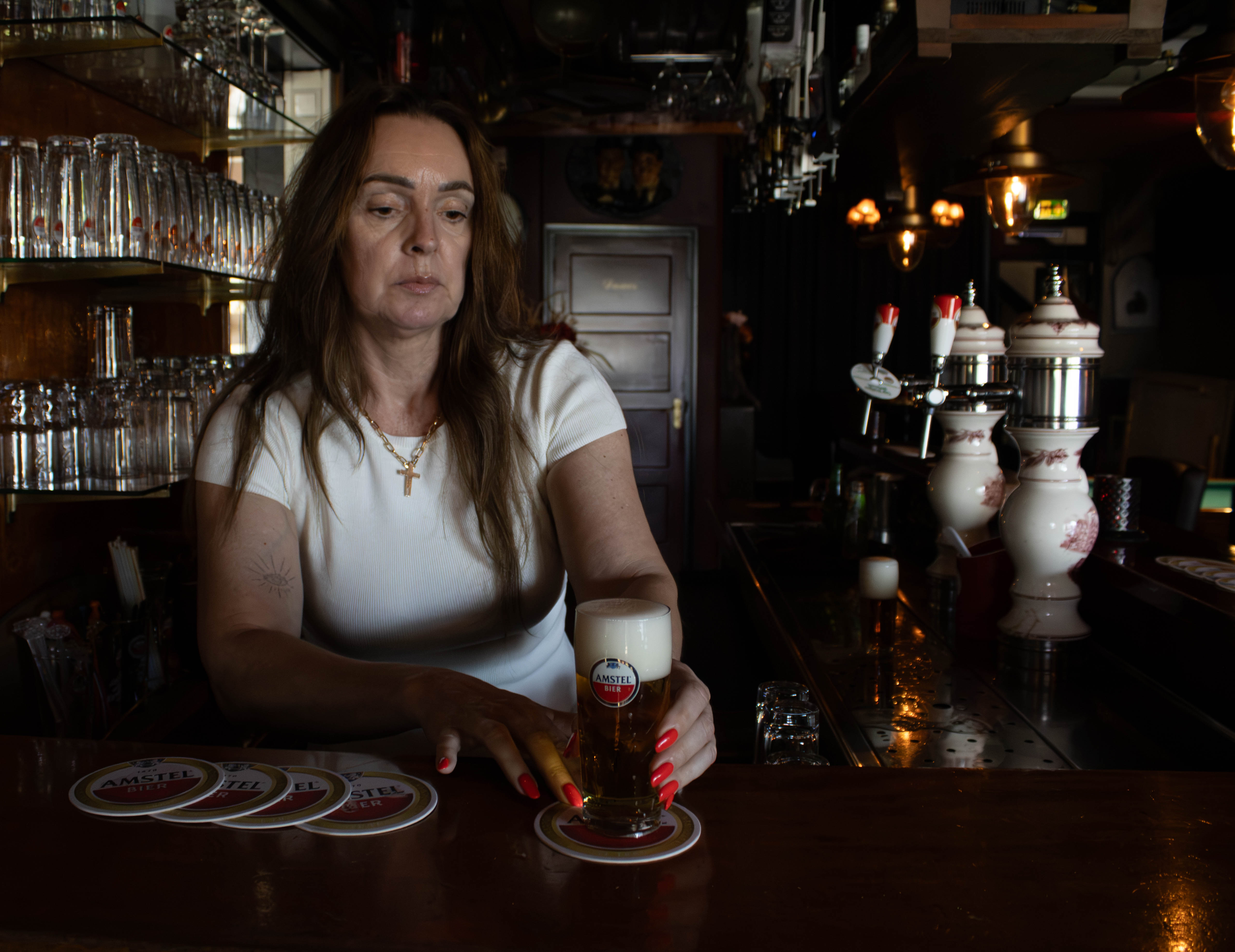 De barvrouw zet een glas bier op een viltje op de bar