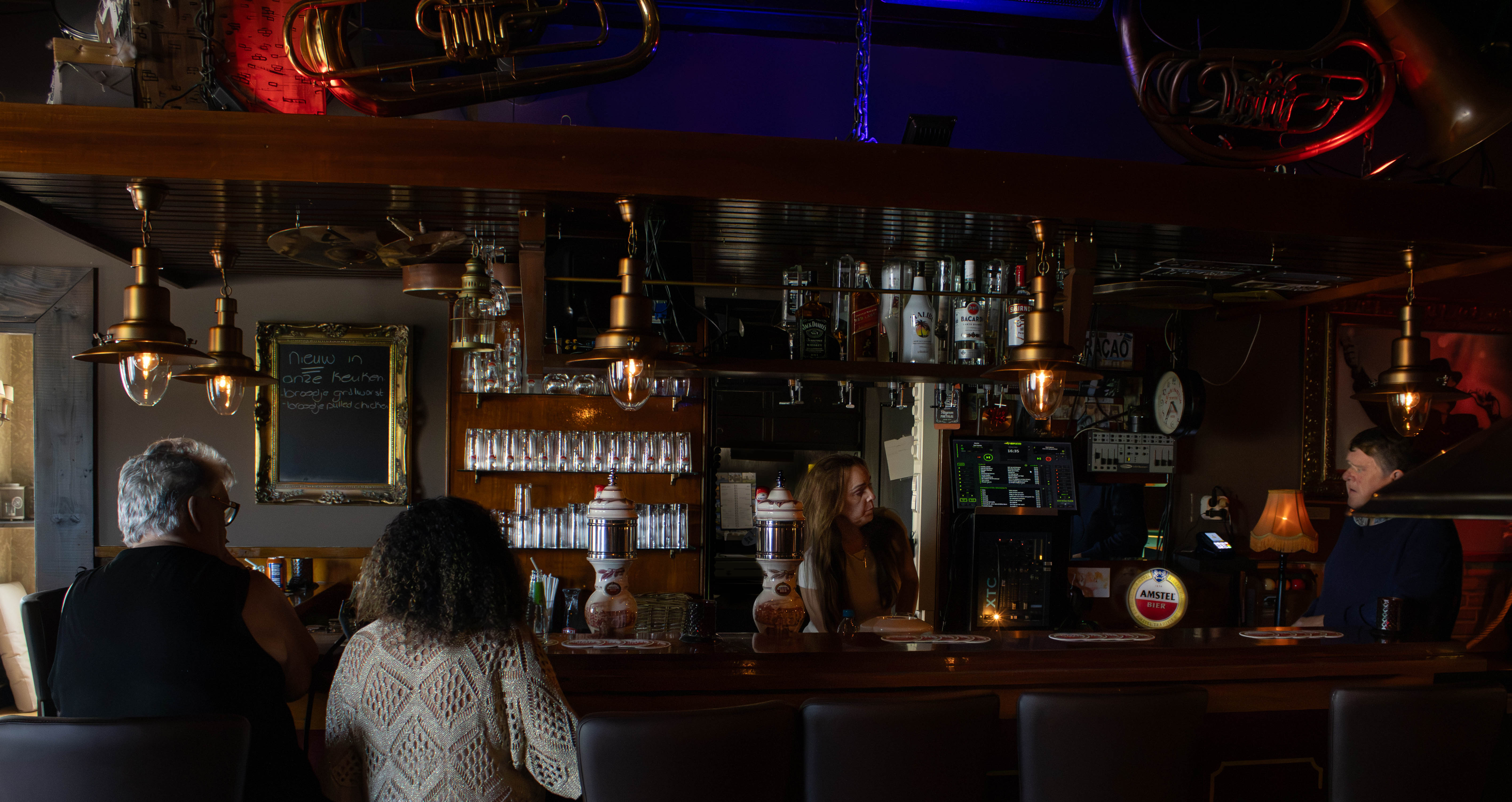 Overzicht van de bar met de eigenaresse en gasten