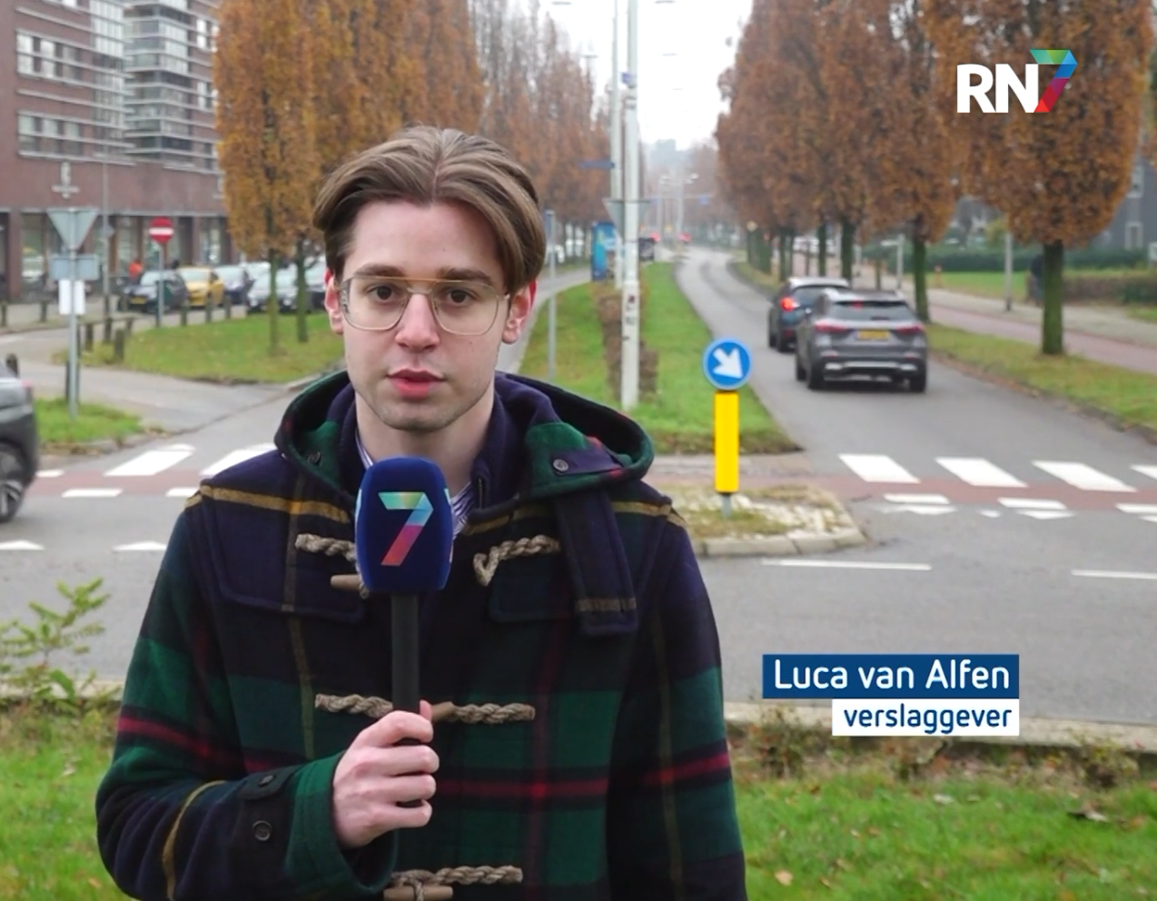 Luca op locatie met een RN7-microfoon, met zijn naam en functie als verslaggever in beeld.